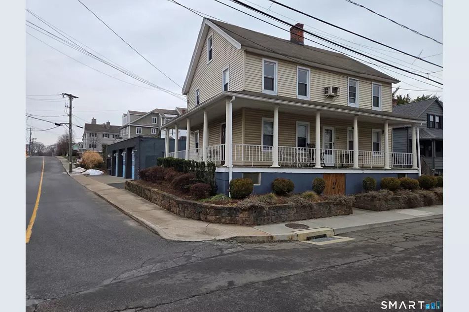 Exterior view of 31 Franklin Street, Historic Saugatuck, Westport CT — the two-family residential building with wraparound porch, with the commercial building visible behind it